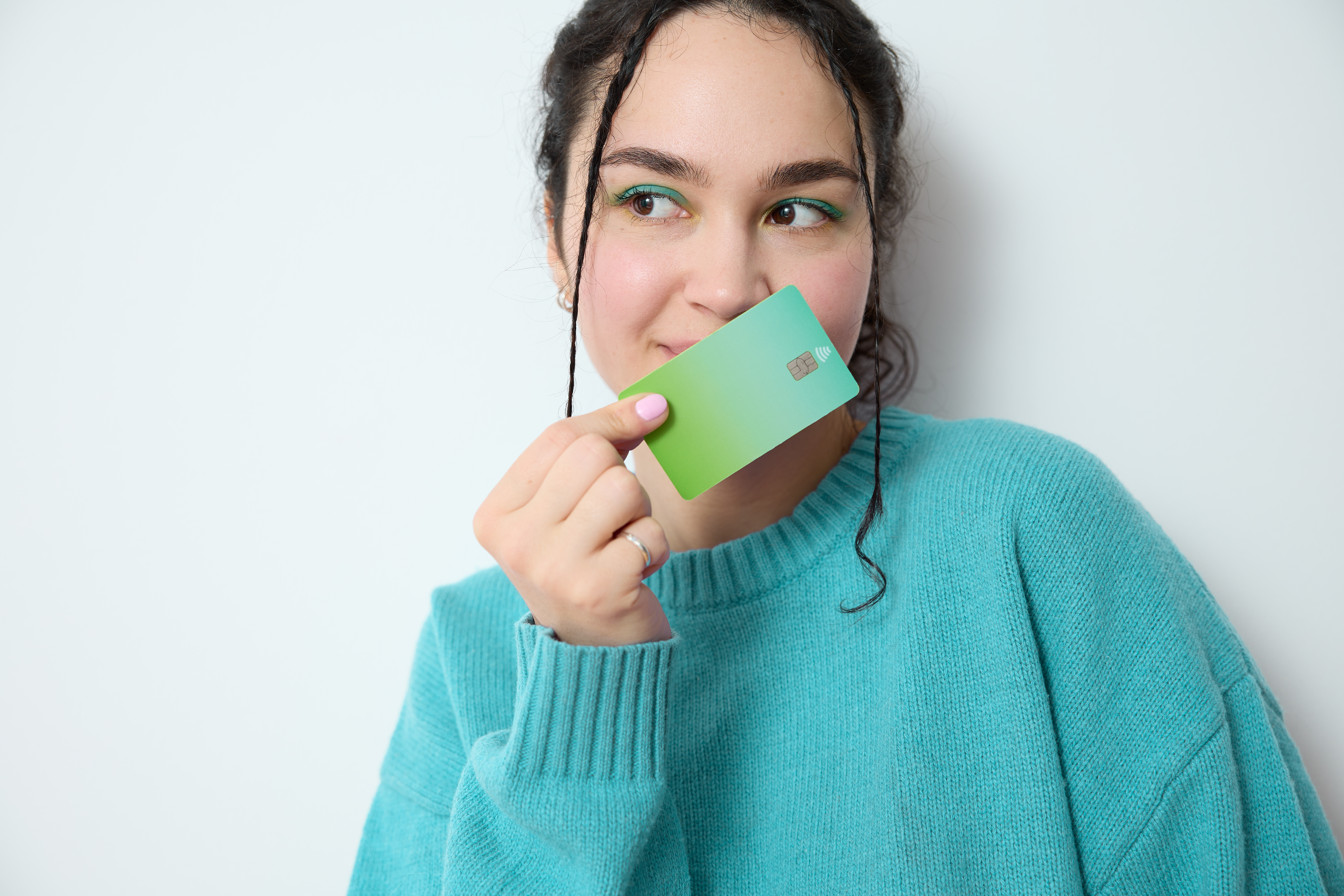 Gen Z girl with a blue sweater on holding up a credit card