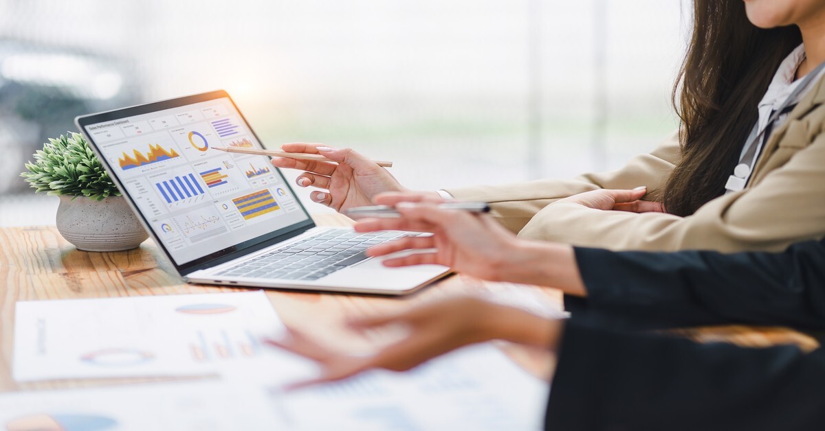Women look at a budgeting dashboard on a laptop together