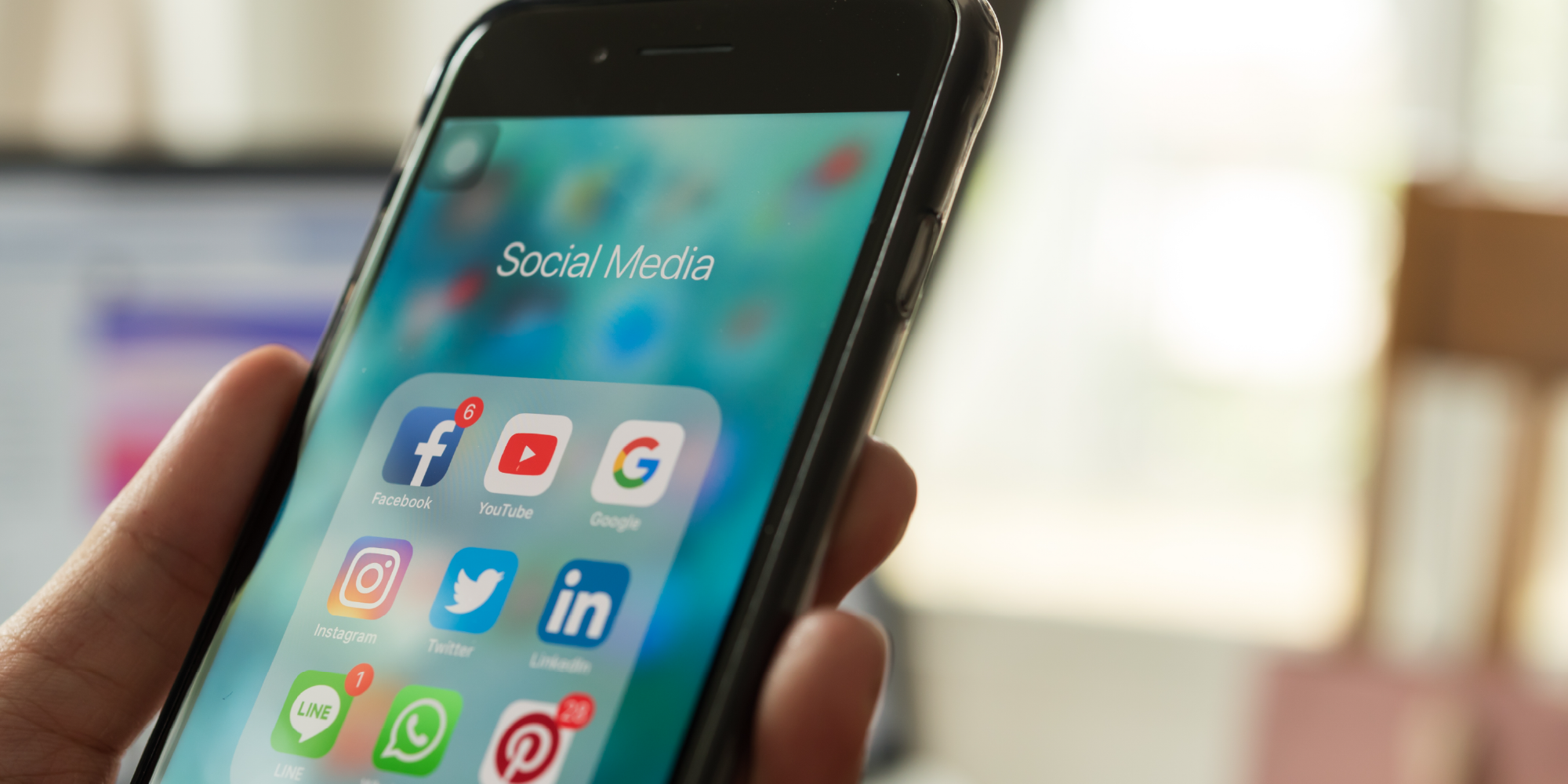 Image of phone in hand with social media icons displayed on the phone screen